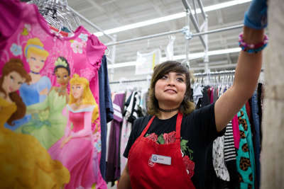 Thrift store worker hangs clothes on hangers
